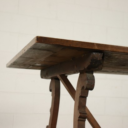 Tavolo a cavalletto realizzato con parti antiche, sorretto da gambe mosse e intagliate, connesse da una traversa, il piano a telaio presenta una stampiglia d'inventario nella parte sottostante.