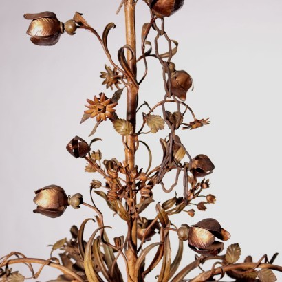 Araña de luces en metal y chapa trabajada con motivos florales, dorada y pintada.